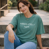 Woman wearing a green t-shirt with 'ABSOLUTELY NOT.' text, sitting outdoors.