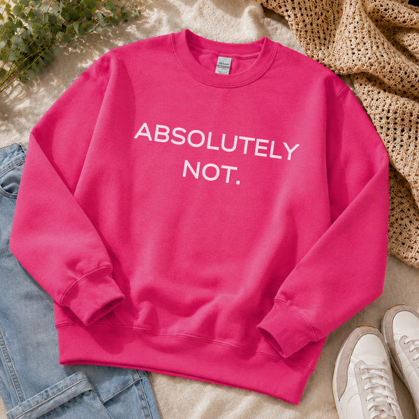 A bright pink crewneck sweatshirt with the text 'ABSOLUTELY NOT.' printed in white across the chest, styled in a flat lay with light blue jeans, a beige knit blanket, and white sneakers.