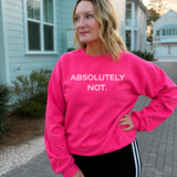 A woman wearing a bright pink crewneck sweatshirt with the text 'ABSOLUTELY NOT.' printed in white across the chest, standing outdoors on a paved walkway in front of houses.