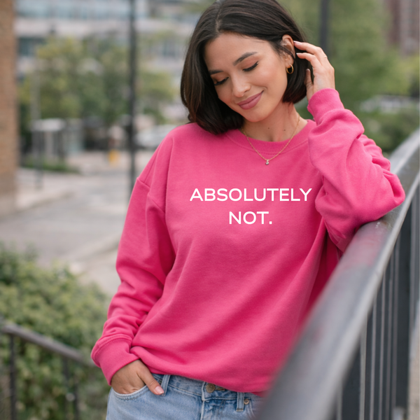 Woman wearing a pink sweatshirt with 'ABSOLUTELY NOT.' text, standing outdoors.