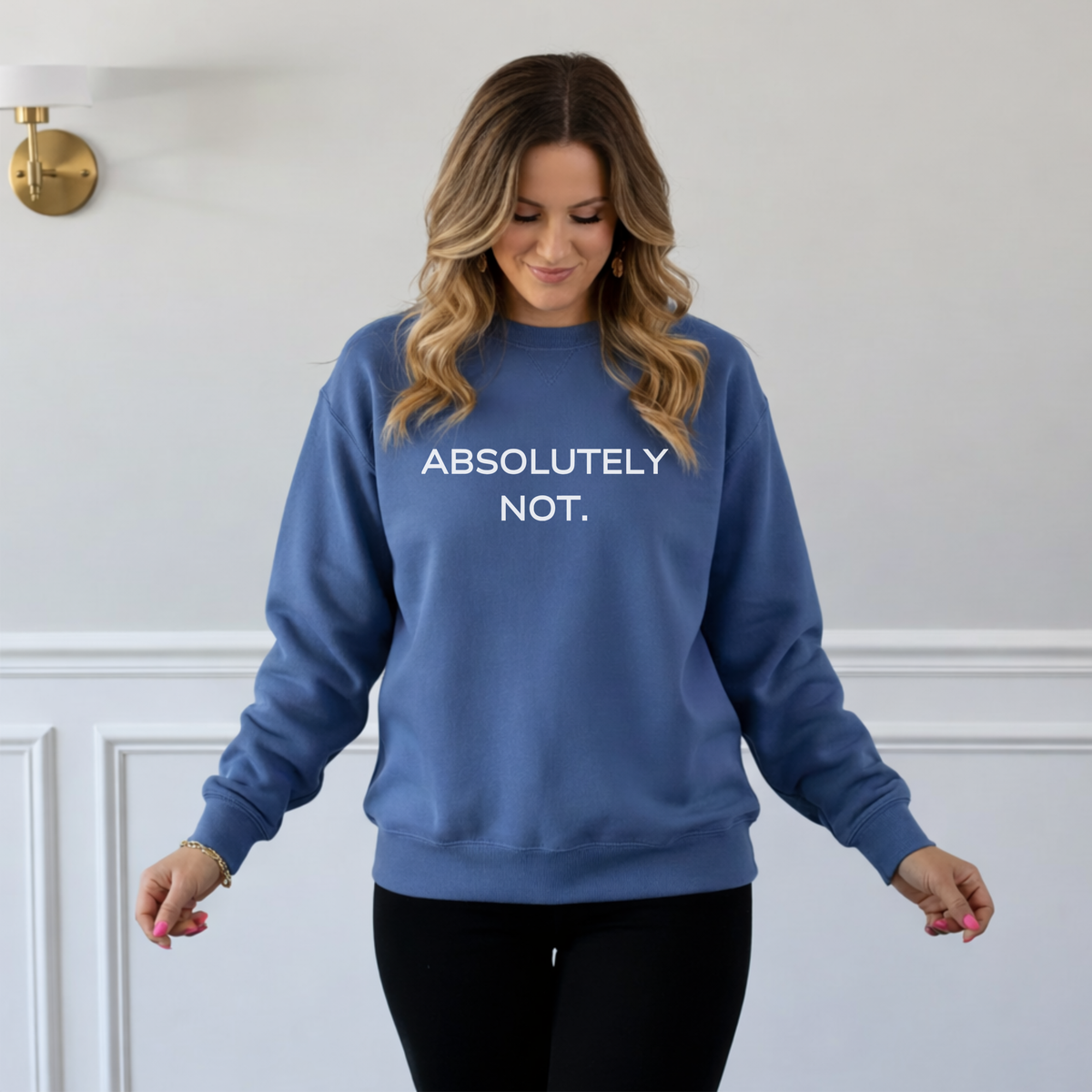Woman wearing a blue sweatshirt with 'ABSOLUTELY NOT.' text against a white wall.