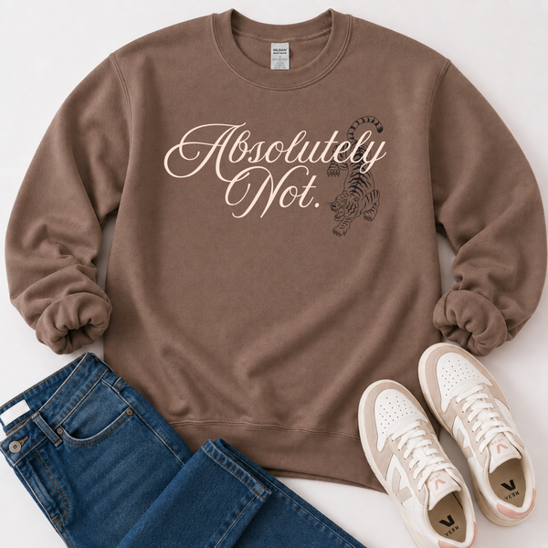A brown crewneck sweatshirt with 'Absolutely Not.' in white script and a black tiger graphic, styled in a flat lay with blue jeans and white sneakers on a white background.