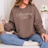 A woman sitting on a couch wearing a brown sweatshirt with the text 'Absolutely Not.' in white script and a small tiger graphic, paired with blue jeans and holding an iced coffee.