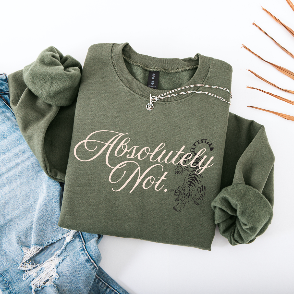 An olive green crewneck sweatshirt with rolled sleeves, featuring the text 'Absolutely Not.' in white script and a black tiger graphic.