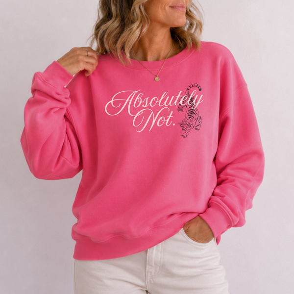 A woman wearing a bright pink crewneck sweatshirt with the text 'Absolutely Not.' in white script and a pink awareness ribbon graphic on the front, paired with white pants against a light gray background.