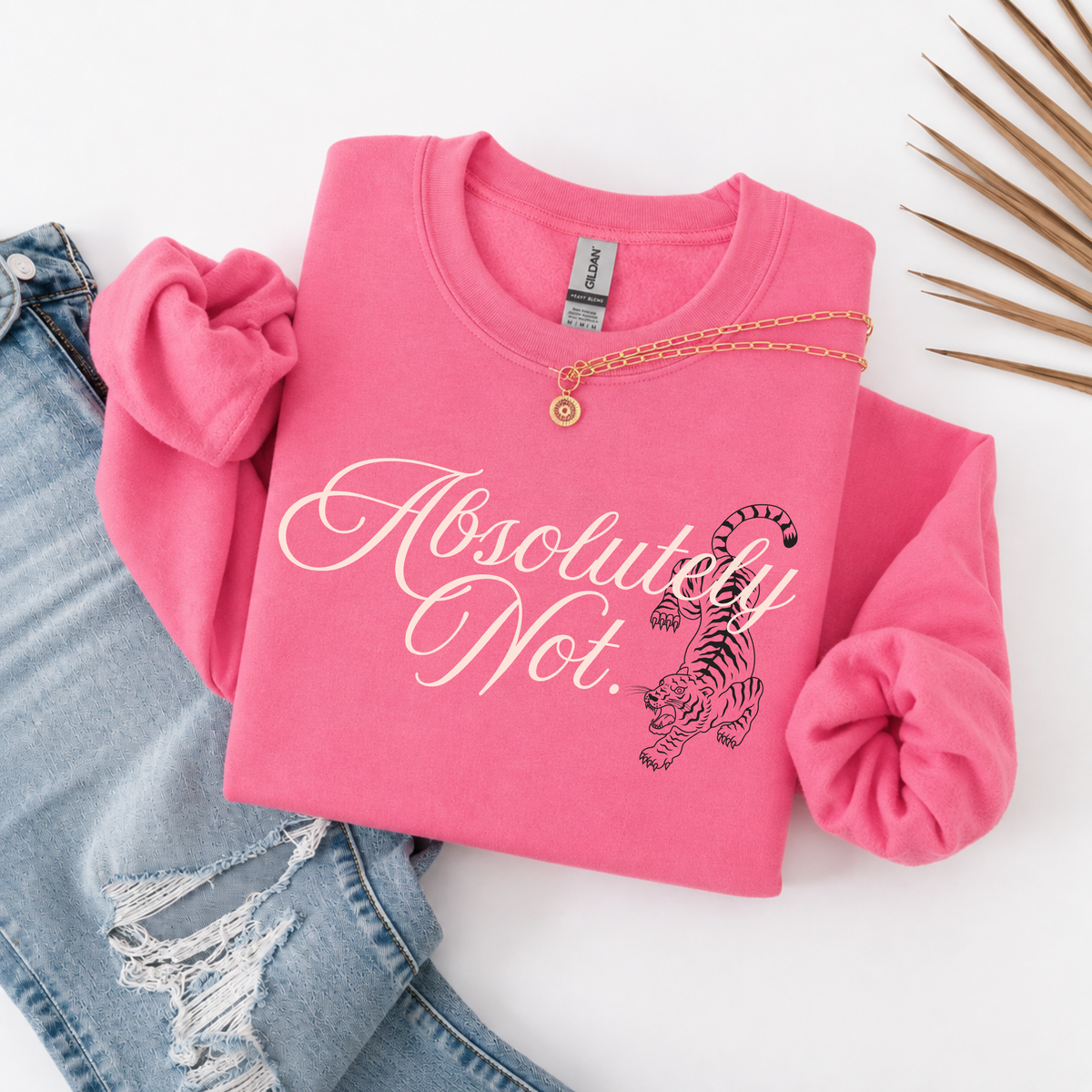 A folded bright pink sweatshirt with rolled sleeves, featuring the words 'Absolutely Not.' in white script and a black-and-pink tiger graphic.