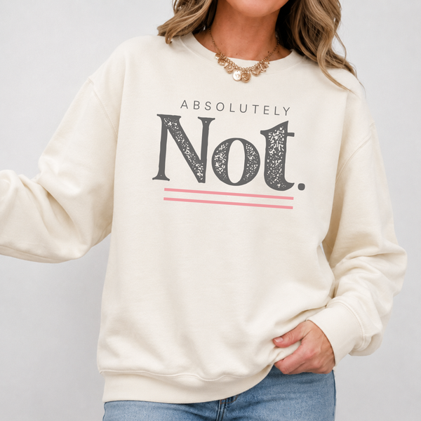 A woman wearing a cream-colored crewneck sweatshirt with a graphic print that reads 'ABSOLUTELY Not.' in dark gray with pink accent lines, paired with blue jeans and a gold necklace.