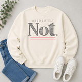 An off-white crewneck sweatshirt with a graphic print reading 'ABSOLUTELY Not.' in dark gray with pink accent lines, styled in a flat lay with blue jeans, white sneakers, and a sprig of green eucalyptus on a light gray background.