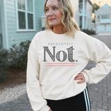 A woman wearing a cream-colored crewneck sweatshirt with a graphic print that reads 'ABSOLUTELY Not.' in dark gray with a pink underline accent, standing outdoors on a paved walkway with houses in the background.