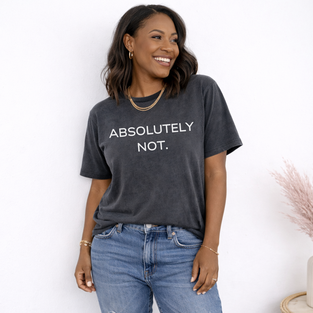 Woman wearing a dark gray t-shirt with 'ABSOLUTELY NOT.' text, standing against a white background.
