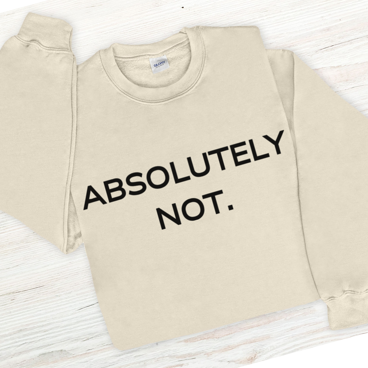 Beige sweatshirt with 'ABSOLUTELY NOT.' text on a light wooden surface