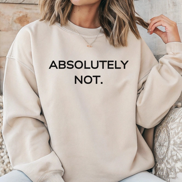 A woman wearing a cream-colored crewneck sweatshirt with the text 'ABSOLUTELY NOT.' printed in black across the chest, sitting in a patterned armchair.