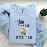 Light blue sweatshirt with 'Anti-Social Book Club' text and book stack graphic on a white marble surface.
