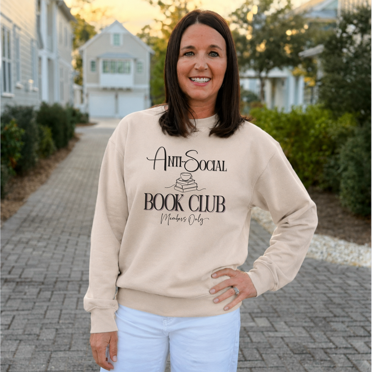 Woman wearing a beige sweatshirt with 'Anti-Social Book Club Members Only' text, standing outdoors.