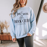 Person wearing a light blue sweatshirt with 'Anti-Social Book Club Members Only' text in a home setting.
