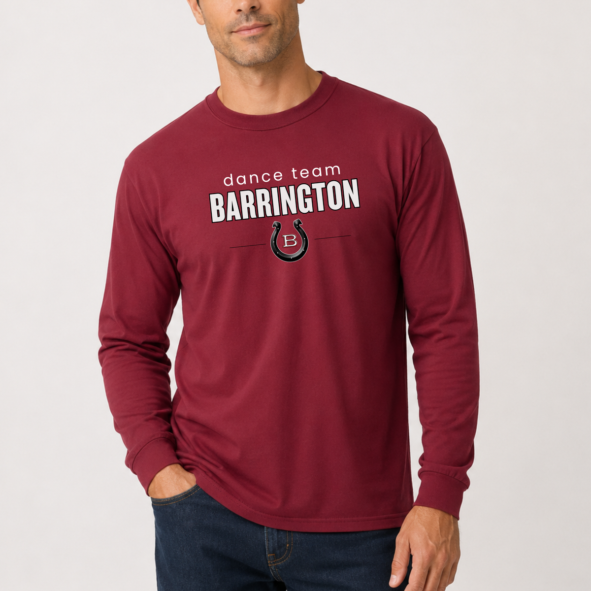 A man wearing a maroon long-sleeve t-shirt with 'dance team BARRINGTON' and a horseshoe logo printed on the chest, paired with dark blue jeans against a light gray background.