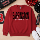 A red crewneck sweatshirt with 'BARRINGTON dance' printed on the front in black and white, laid flat on a light wood background with cheerleader pom-poms, a water bottle, and white sneakers.