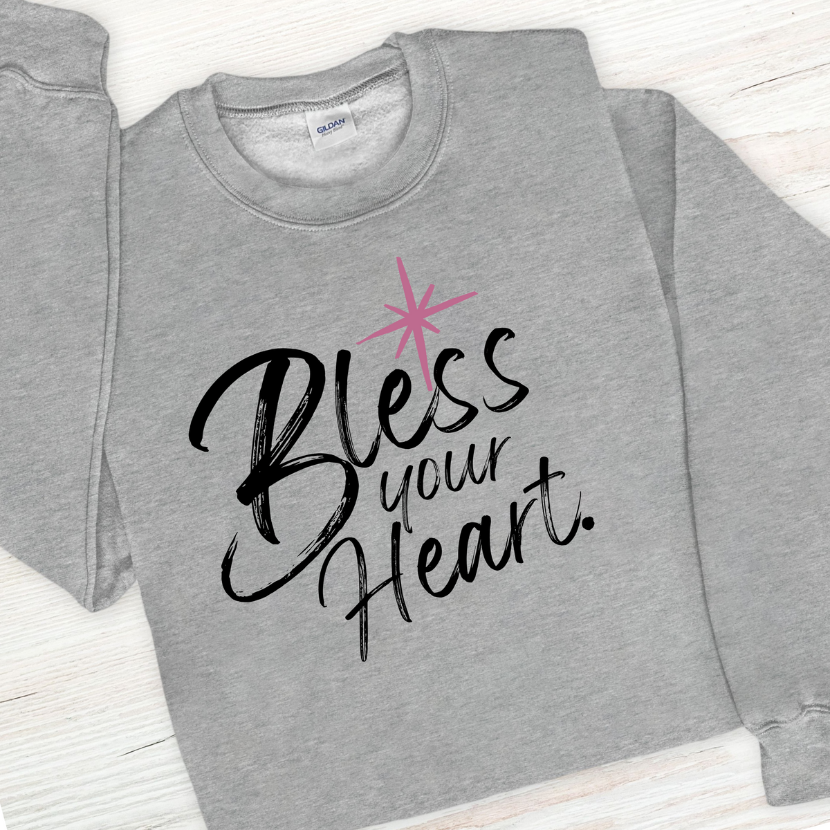 Gray sweatshirt with 'Bless your Heart' text and pink star design on a white background