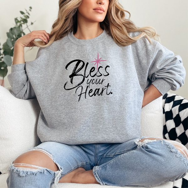 Woman wearing a gray sweatshirt with 'Bless your Heart' text sitting on a couch.