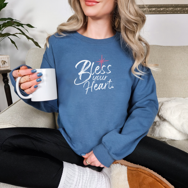 Person wearing a blue sweatshirt with 'Bless your Heart' text, holding a white mug.