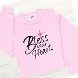 Pink sweatshirt with 'Bless your Heart' text on a light wooden surface