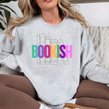 Woman wearing a gray sweatshirt with 'BOOKISH' in colorful letters, sitting on a couch.