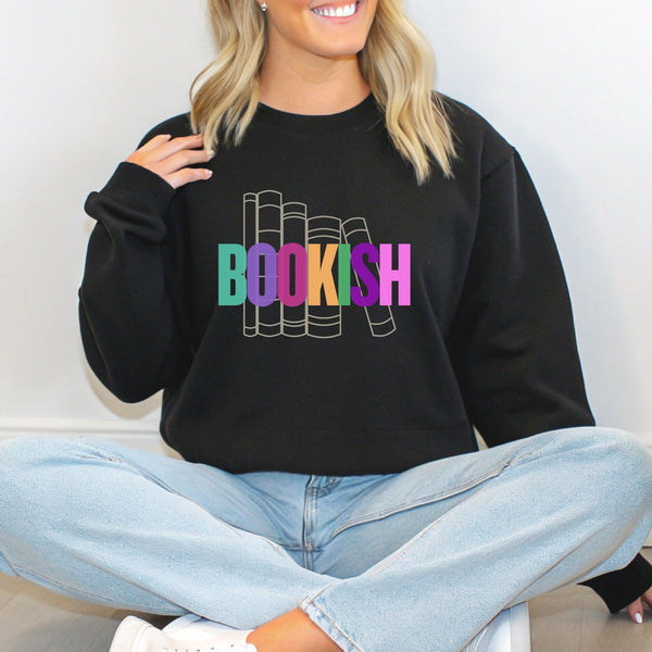 A woman sitting wearing a black sweatshirt with 'BOOKISH' in colorful letters.