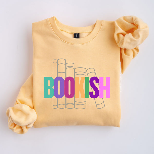 Yellow sweatshirt with 'BOOKISH' colorful text and book illustrations on a light gray background