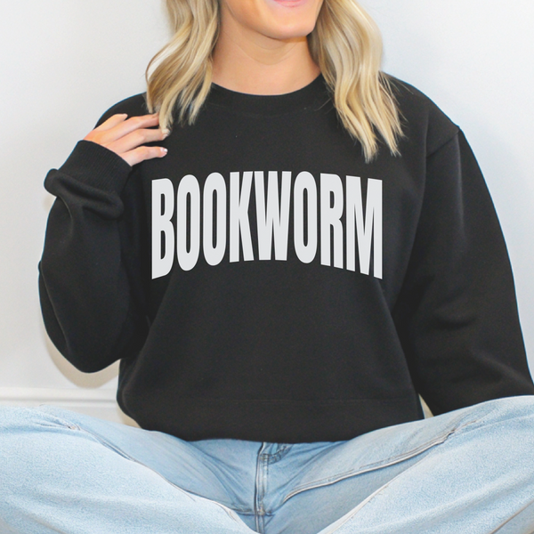 Person wearing a black sweatshirt with 'BOOKWORM' text, sitting against a white background