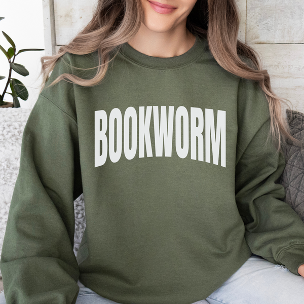 Person wearing a green 'BOOKWORM' sweatshirt sitting on a couch.