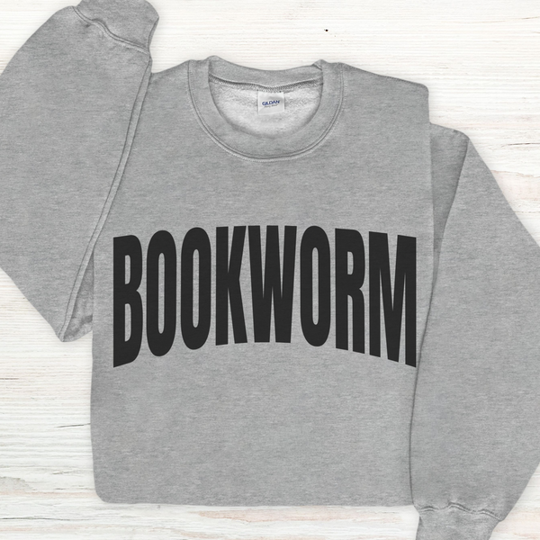 Gray sweatshirt with 'BOOKWORM' text on a light wooden surface