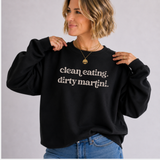 A woman wearing a black crewneck sweatshirt with the text 'clean eating. dirty martini.