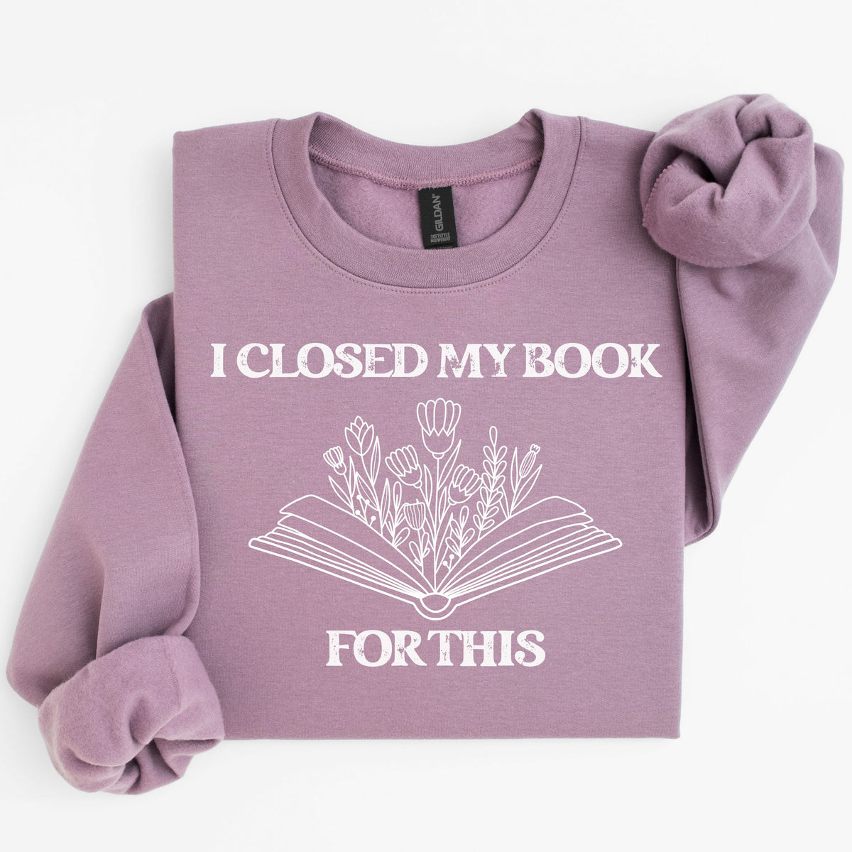 Purple sweatshirt with 'I Closed My Book For This' text and floral design on a white background