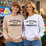 Two women wearing sweatshirts in a football party setting with 'I'm just here for the commercials' text in a casual outfit.
