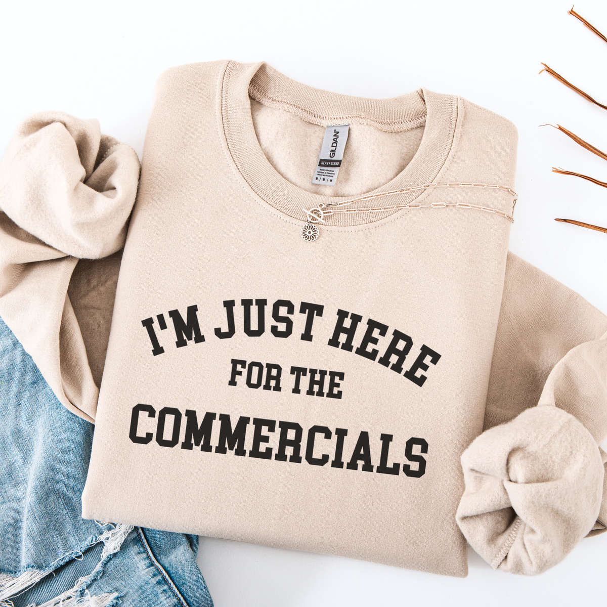 Beige sweatshirt with 'I'm just here for the commercials' text on a white background