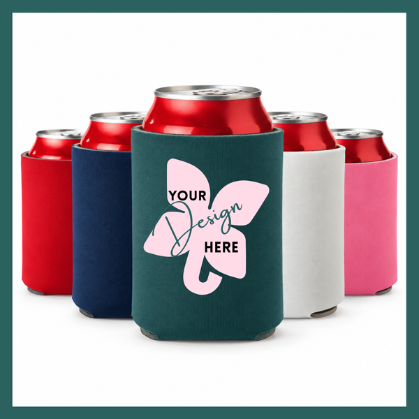 A custom can cooler in dark teal shown in the foreground, with red, navy, white, and pink can coolers behind it on a white background. The front can cooler has a pink elephant graphic with the text 'YOUR Design HERE'.