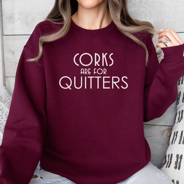 Person wearing a maroon sweatshirt with 'Corks are for Quitters' text.