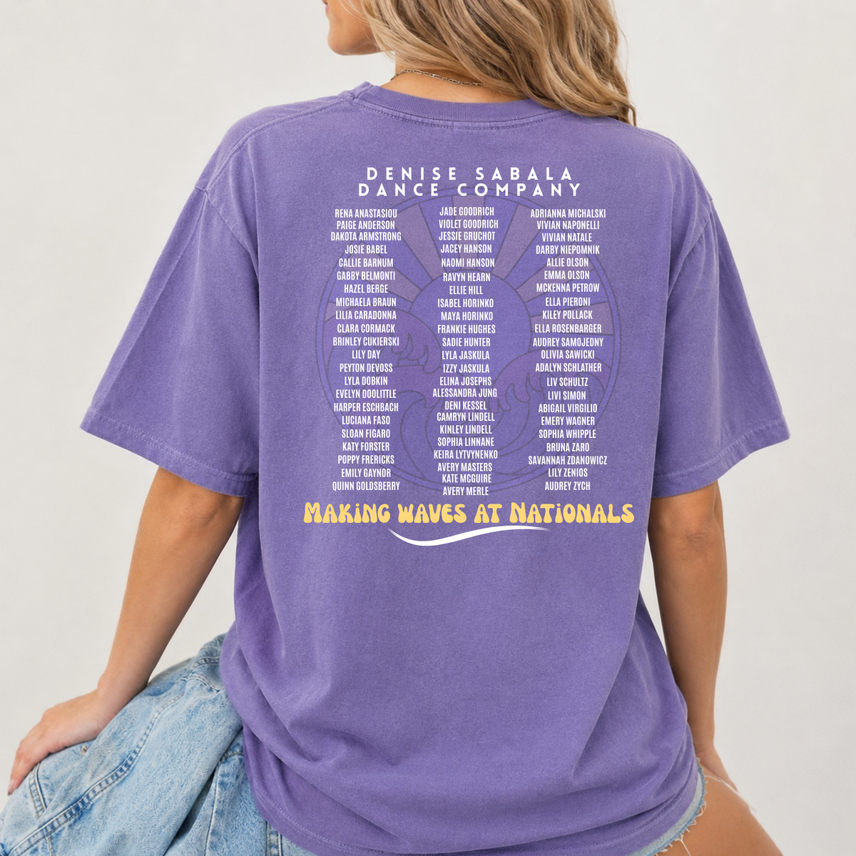 Purple t-shirt with text on the back worn by a person, against a plain background