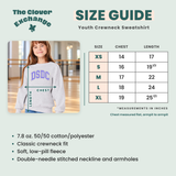 A size guide infographic for a youth crewneck sweatshirt by The Clover Exchange. It features a size chart table from XS to XL with chest and length measurements in inches, a product photo of a girl wearing a gray sweatshirt with purple 'DSDC' lettering, and a list of fabric and fit details at the bottom.