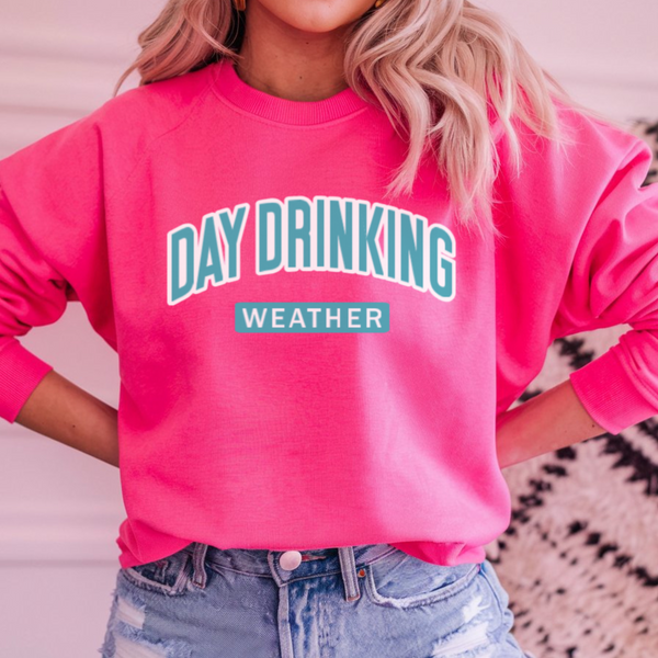 Woman wearing a bright pink Sweatshirt with "Day Drinking Weather" in aqua blue font.