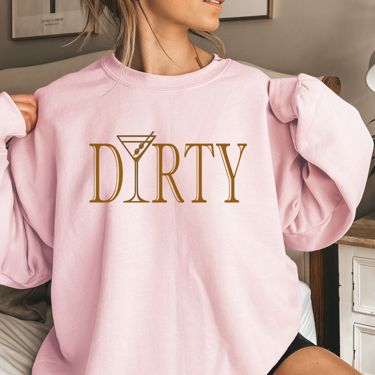 Person wearing a pink sweatshirt with 'DIRTY' printed in gold. The letter "i" in 'martini' is a martini glass.