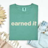 A folded light green tee shirt that says 