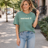 A woman in jeans and a light green tee shirt that says 