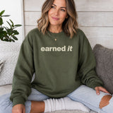 A woman sitting in a dark green sweatshirt with the words 