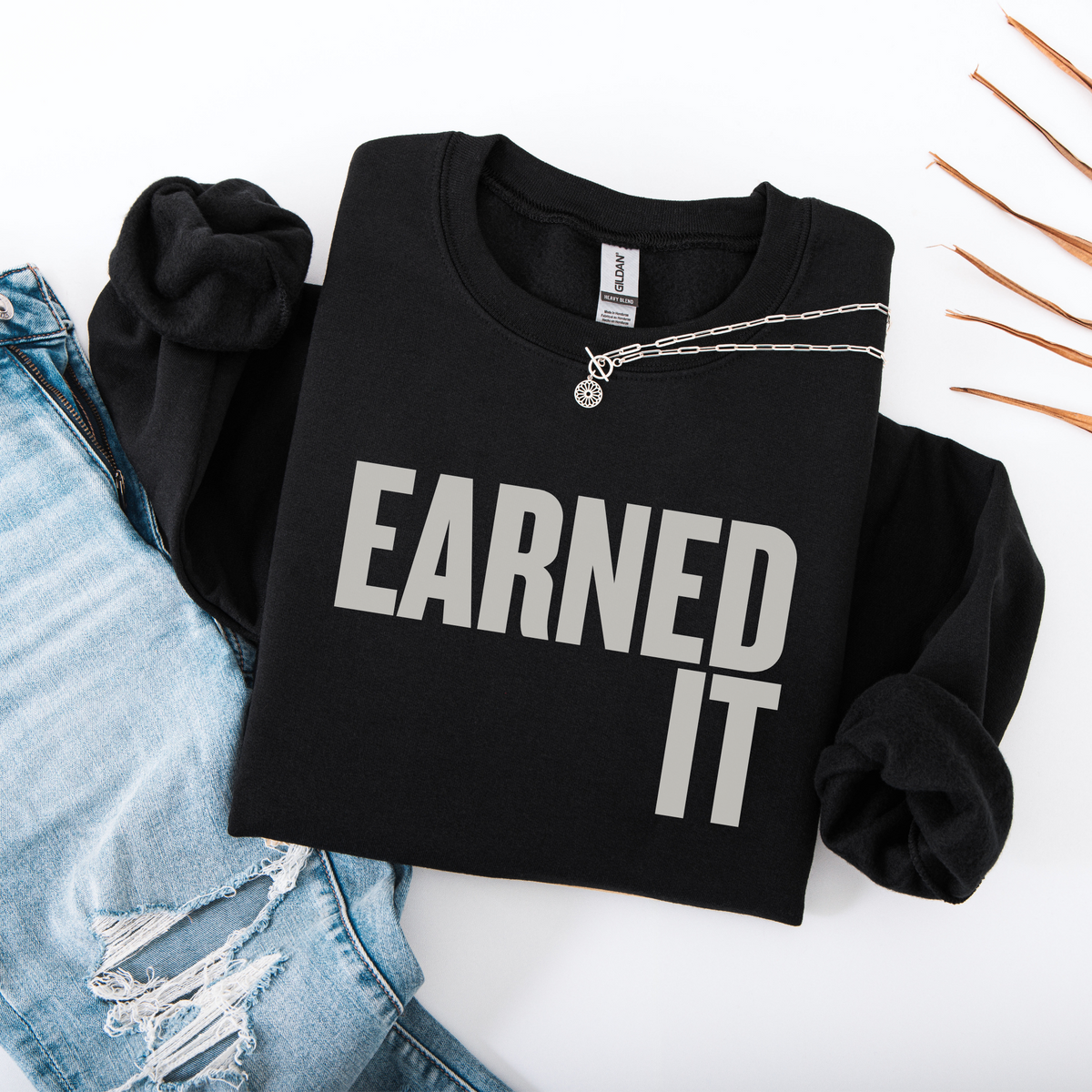 A folded black sweatshirt with the words "Earned It" in light gray font.