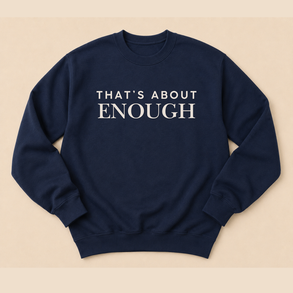 A navy blue crewneck sweatshirt with the text 'THAT'S ABOUT ENOUGH' printed in white serif letters across the chest, displayed flat against a light beige background.