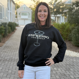 Woman wearing a black sweatshirt with 'Espresso Yourself' text and a coffee cup graphic, standing outdoors.