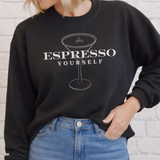 Person wearing a black sweatshirt with 'Espresso Yourself' design against a light gray background