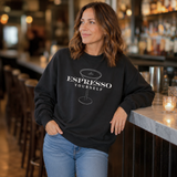 Woman wearing a black sweatshirt with 'Espresso Yourself' text in a bar setting