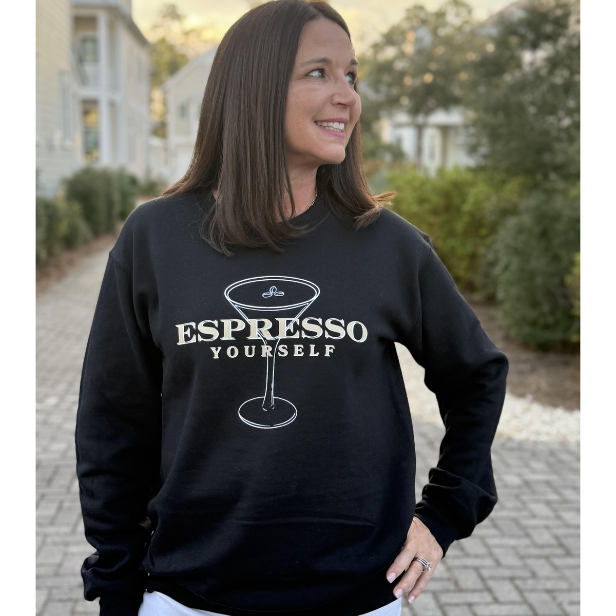 Woman wearing a black sweatshirt with 'Espresso Yourself' text and coffee cup graphic.